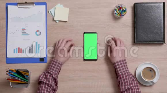 一个男人的手触摸智能手机上绿色屏幕的右上角视频的预览图