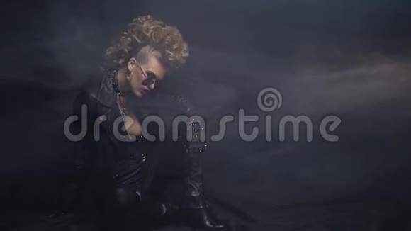 身穿黑色皮衣发型疯狂的摇滚女孩在烟雾中在地板上摆姿势视频的预览图