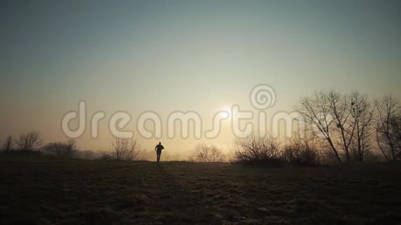 一个在阳光下奔跑的人的剪影背景上的日出或日落视频的预览图