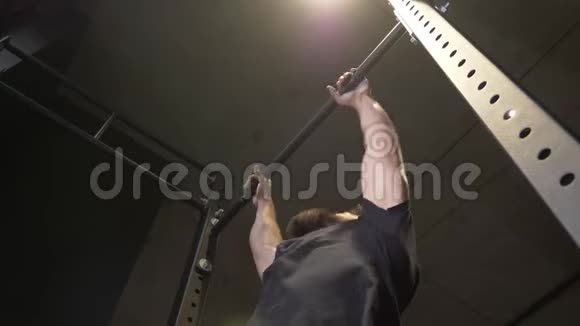 成年肌肉运动员在健身房的酒吧里蹦蹦跳跳的特写镜头视频的预览图