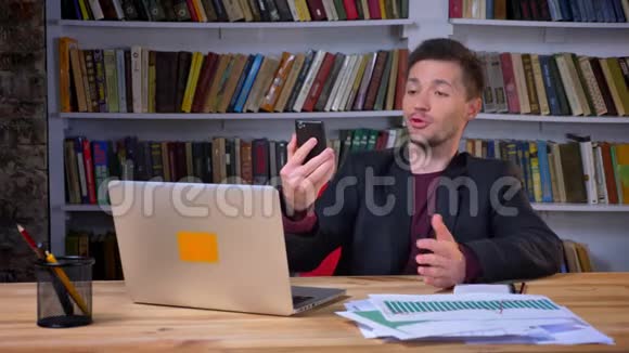 有魅力的积极商人坐在笔记本电脑前通过电话进行视频通话在视频的预览图