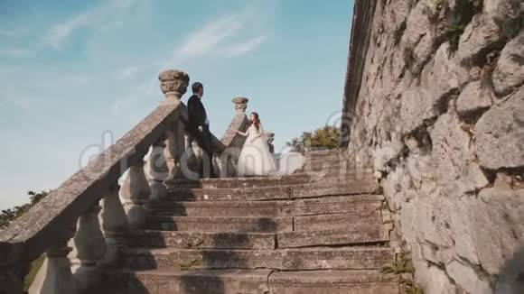 幸福的新婚夫妇站在城堡楼梯上摆姿势视频的预览图