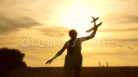 年轻女孩带着一架玩具飞机在田野上奔跑在阳光下孩子们玩玩具飞机少年梦想视频的预览图
