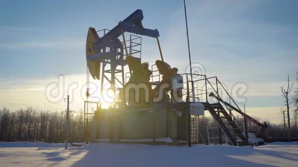 油泵在冬天的一块田中间太阳下山视频的预览图