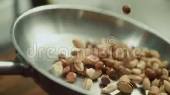 在金属锅上煎炸的坚果混合物特写坚果在缓慢运动中翻滚视频的预览图