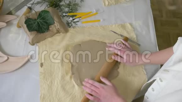 陶工工匠用擀面杖在桌子上滚动粘土以便在车间制作陶器俯视视频的预览图