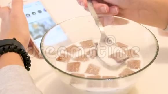 少女在早上吃早餐一天的开始带有牛奶的特写透明盘子视频的预览图