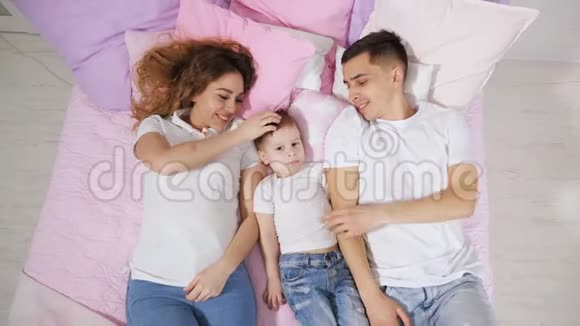 幸福的一家人在床上妈妈儿子和爸爸在一起接吻和拥抱视频的预览图