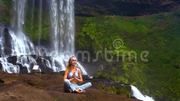 女孩在瀑布石上冥想普拉纳亚瑜伽姿势视频的预览图
