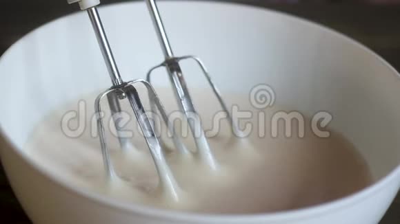 糕点厨师用奶油从杯子里拿出电动搅拌器的刀片视频的预览图