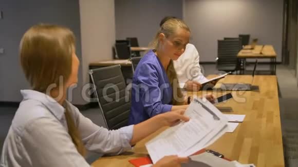 年轻的女商人坐在办公桌前看一些文件视频的预览图