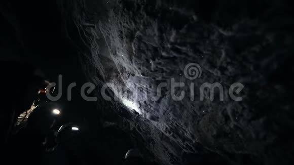 一个潮湿的岩石洞穴人们在洞穴中探索一堵布满矿物的墙视频的预览图
