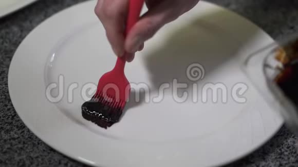 厨师手在盘子上涂上厚厚的桑拿浴用红色橡胶刷在现代餐厅关门厨师装饰视频的预览图