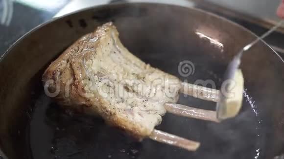 厨师手加入一块黄油用勺子在煎锅中加入多汁的肋骨然后拿走锅厨师视频的预览图