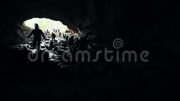 一个潮湿的岩石洞穴在黑暗中行走的探险者视频的预览图