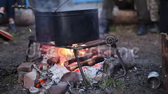 人们用篝火在金属桶里加热水把木柴扔进火里视频的预览图