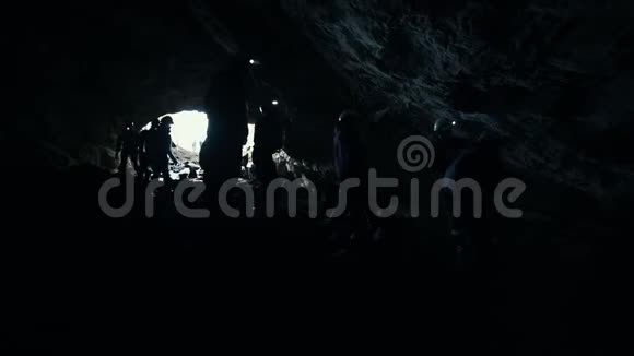 一个潮湿的岩石洞穴人们用灯光设备探索黑暗的洞穴视频的预览图