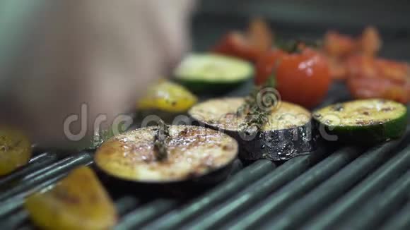 厨师手检查蔬菜番茄茄子西葫芦黄铃椒在烤架上用金属钳子合上视频的预览图