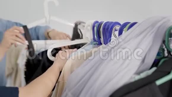 两个女人白天在更衣室里摸挂在衣架上的衣服手举起来选择视频的预览图