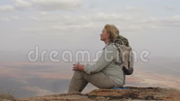 女游客坐在山顶欣赏迷人的景色和成功视频的预览图