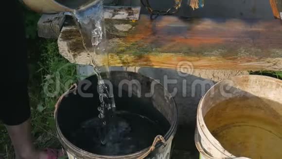 女孩把水倒进水桶里女人用水桶把链条滴到乡村井里打水视频的预览图