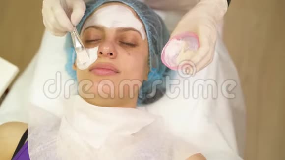年轻女子接受美容药物治疗特写美容师双手在工作清洁皮肤做面部按摩视频的预览图