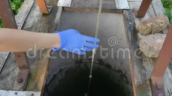 女人用水桶把链条滴到乡村井里打水女孩把水倒进水桶里视频的预览图
