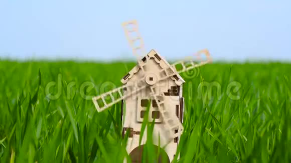 磨坊叶片在风中旋转一个小的装饰磨坊矗立在一片绿草的田野里视频的预览图