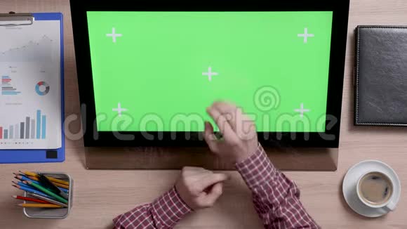 一个人的手触到显示器上绿色屏幕中心的俯视图视频的预览图