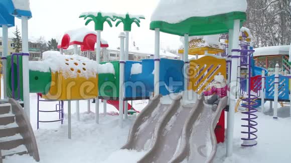 小女孩在白雪覆盖的游乐场玩耍视频的预览图