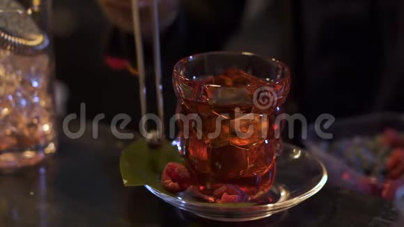 酒吧里准备鸡尾酒的酒保酒吧老板把蓝莓和覆盆子放在靠近酒精玻璃的盘子里视频的预览图