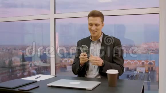 坐在工作场所时用放大镜检查钢笔的男性专家视频的预览图