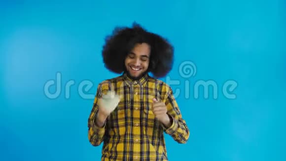快乐的年轻非裔美国人手里拿着钱看着蓝色背景上的相机视频的预览图