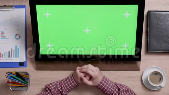 顶视图男子的手使用触摸屏的大显示器与绿色屏幕上视频的预览图