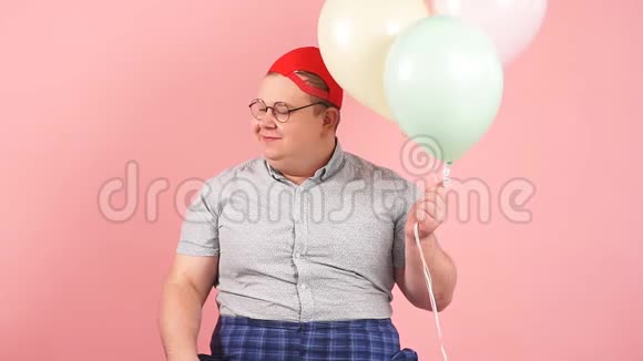 快乐的男人穿着孩子气的衣服手里拿着气球开心地笑着慢动作视频的预览图