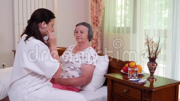 家庭医生在家用听诊器检查老年妇女视频的预览图