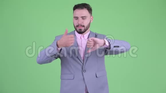 困惑的年轻大胡子商人在竖起大拇指和竖起大拇指之间做出选择视频的预览图