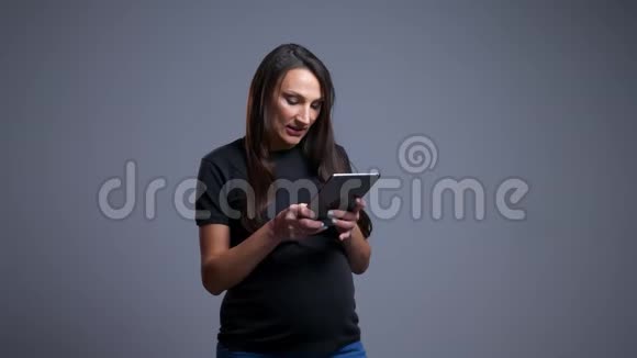 镜头前在平板电脑上打字的年轻白种人孕妇的特写照片视频的预览图