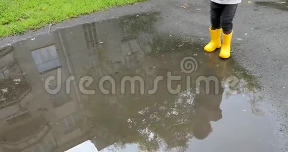 婴儿穿着黄色的橡胶靴子踩水坑视频的预览图
