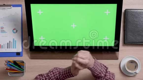 一个男人的手的俯视图触摸到触摸屏上绿色屏幕的右上角视频的预览图