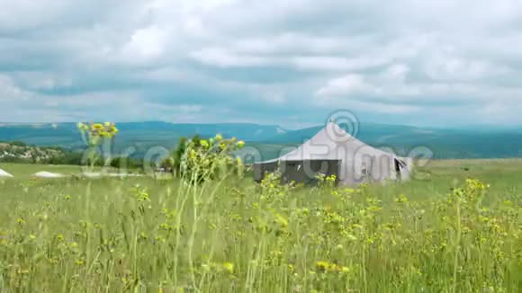 一个大的帆布帐篷矗立在山里的一片田野中间视频的预览图