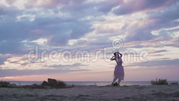 可爱的年轻女人化妆闪闪发光穿着粉红色的裙子在户外跳舞一个温柔的女孩带着一朵花跳舞视频的预览图