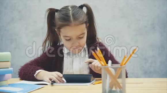 聪明的女学生坐在桌子旁在这期间他写了一个家庭作业数着计算器视频的预览图