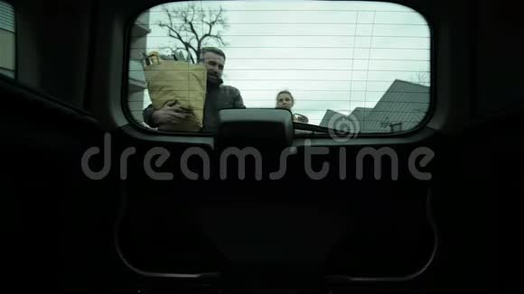 年轻夫妇用新鲜食物包装购物袋进入汽车后备箱从车内看视频的预览图