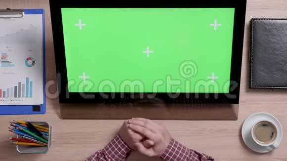 在绿色屏幕触摸显示器的左侧滚动着人的双手的俯视图视频的预览图