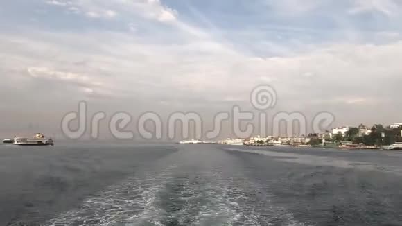 时光舟带着游客游过伊斯坦布尔海岸带着美丽的房子在水上留下一条小径视频的预览图
