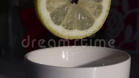 一个人把柠檬汁挤到一个杯子里柠檬新鲜多汁可见汁液滴入杯中近距离射击视频的预览图