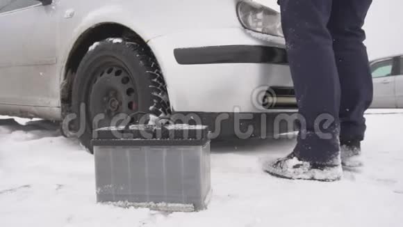 冬天一个男人在汽车里安装了一个新电池它正在下雪运动缓慢视频的预览图