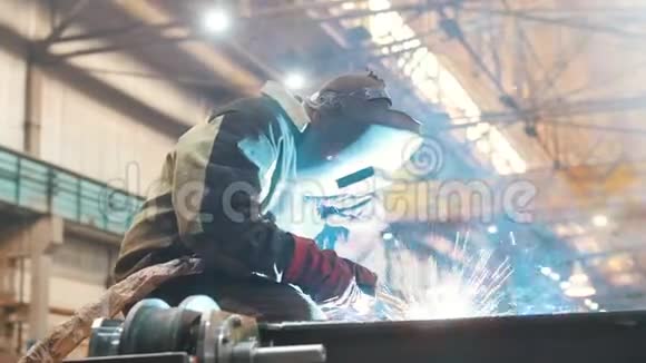 建筑工厂一个戴着头盔的工人在金属细节上使用焊机火焰闪耀视频的预览图