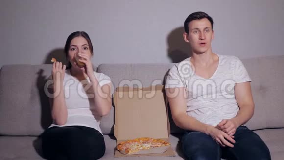 这对幸福的夫妇在沙发上吃披萨看电影视频的预览图